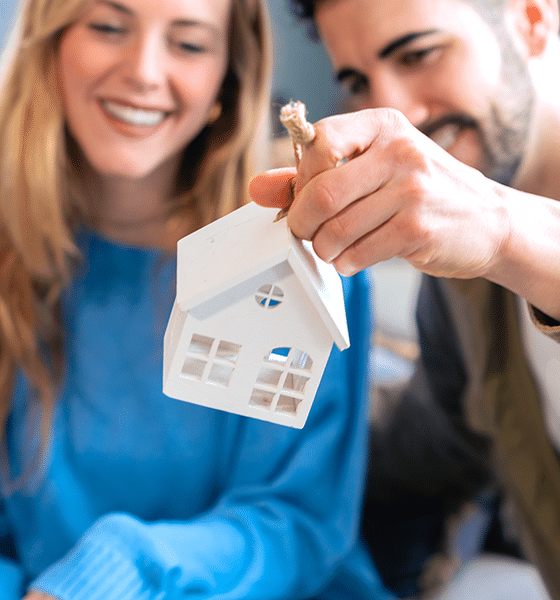 Een koppel houdt een wit speelgoed huis vast